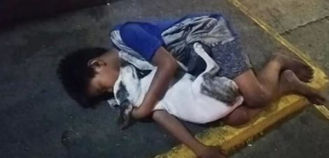 Bimbo senzatetto dorme sul marciapiede abbracciato al cane: la foto simbolo di miseria e amicizia