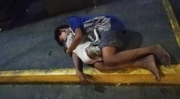 Bimbo senza tetto dorme sul marciapiede abbracciato a un cane: la foto fa il giro del web